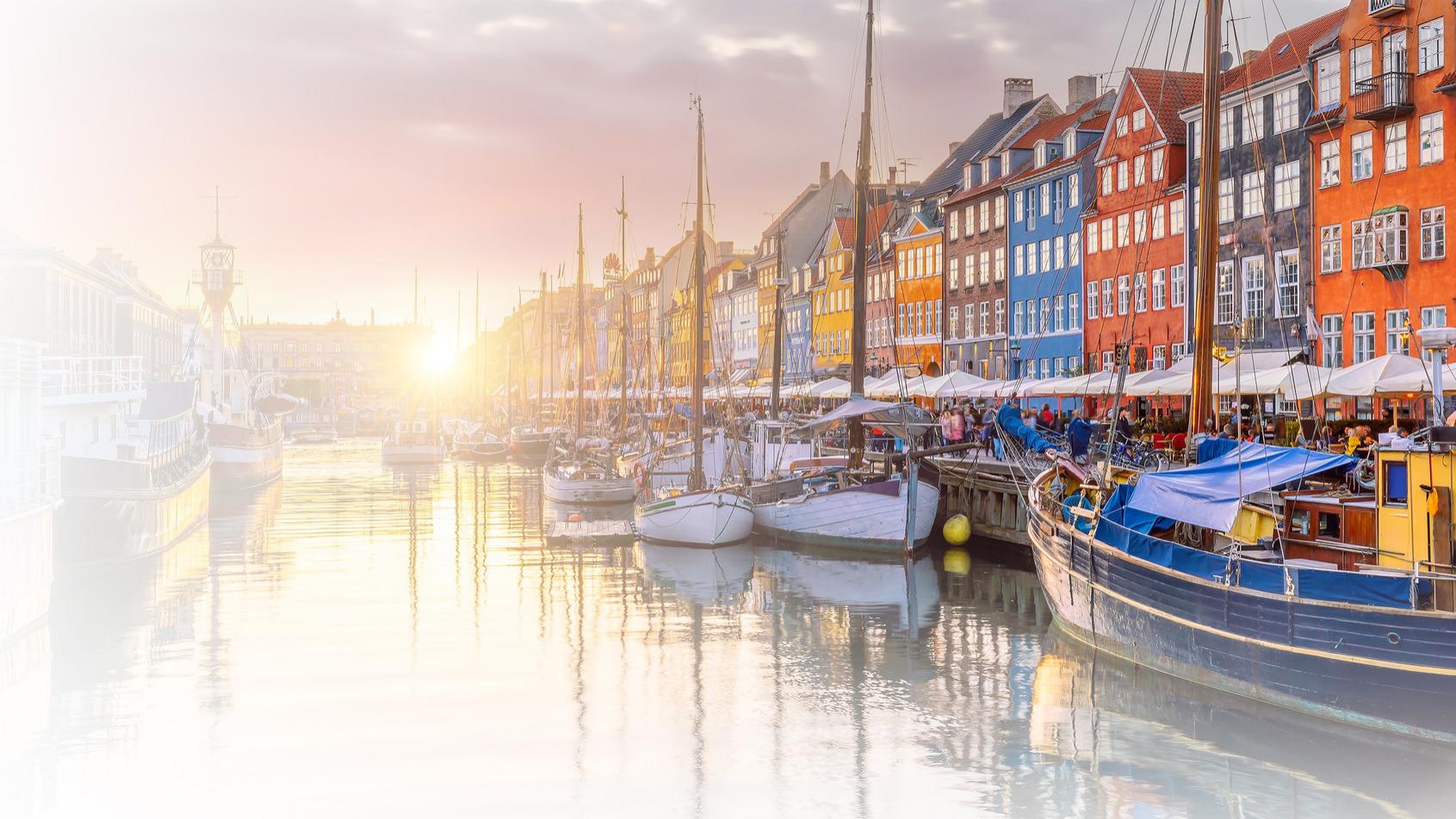 Colorful historic buildings line the waterfront of Copenhagen’s Nyhavn district, with sailboats docked along the calm canal under a vibrant sky, captured in high clarity to showcase ZEISS imaging quality.