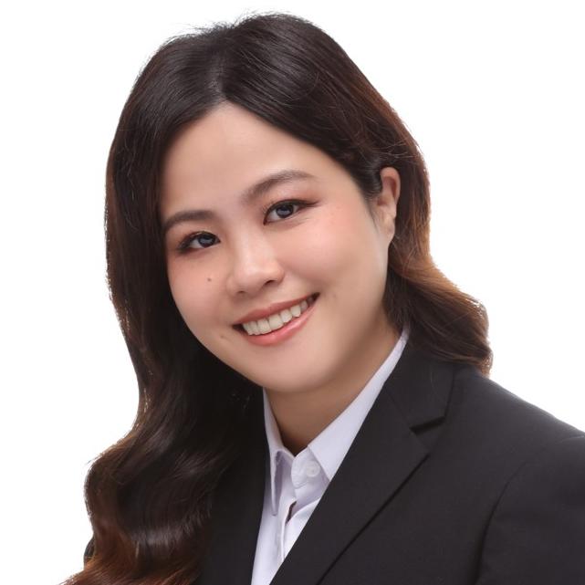A woman in a black blazer and white shirt is smiling against a plain white background.