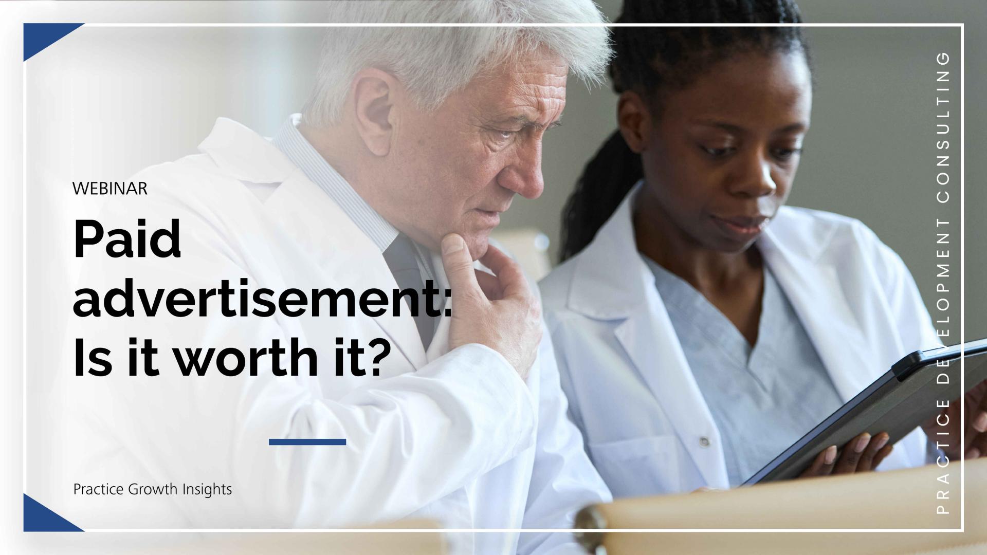 Two medical professionals in white lab coats are examining a tablet together in a clinical setting.