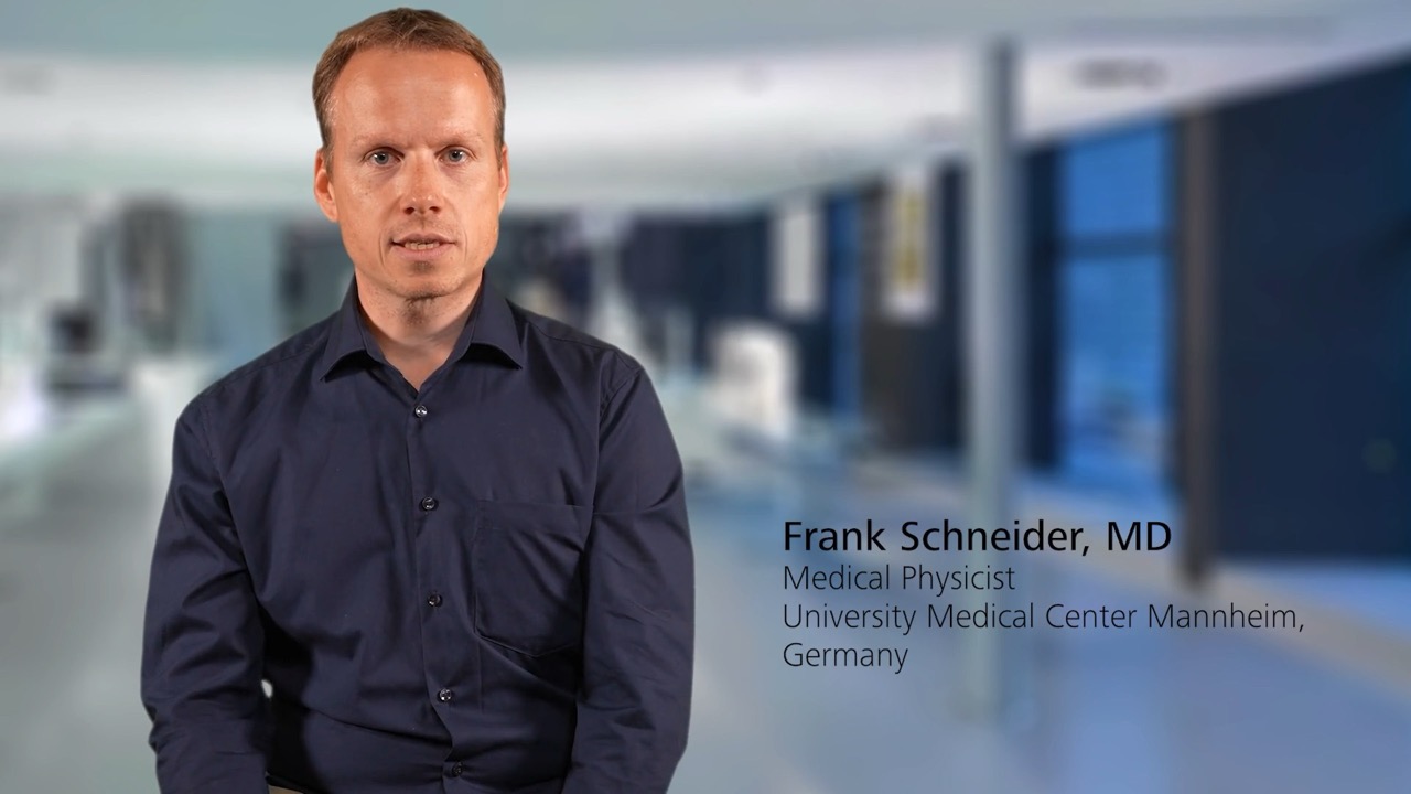 Frank Schneider, MD, Medical Physicist at University Medical Center Mannheim, Germany is seated and speaking in a modern medical facility, background features a blurred clinical environment with ZEISS branding context.