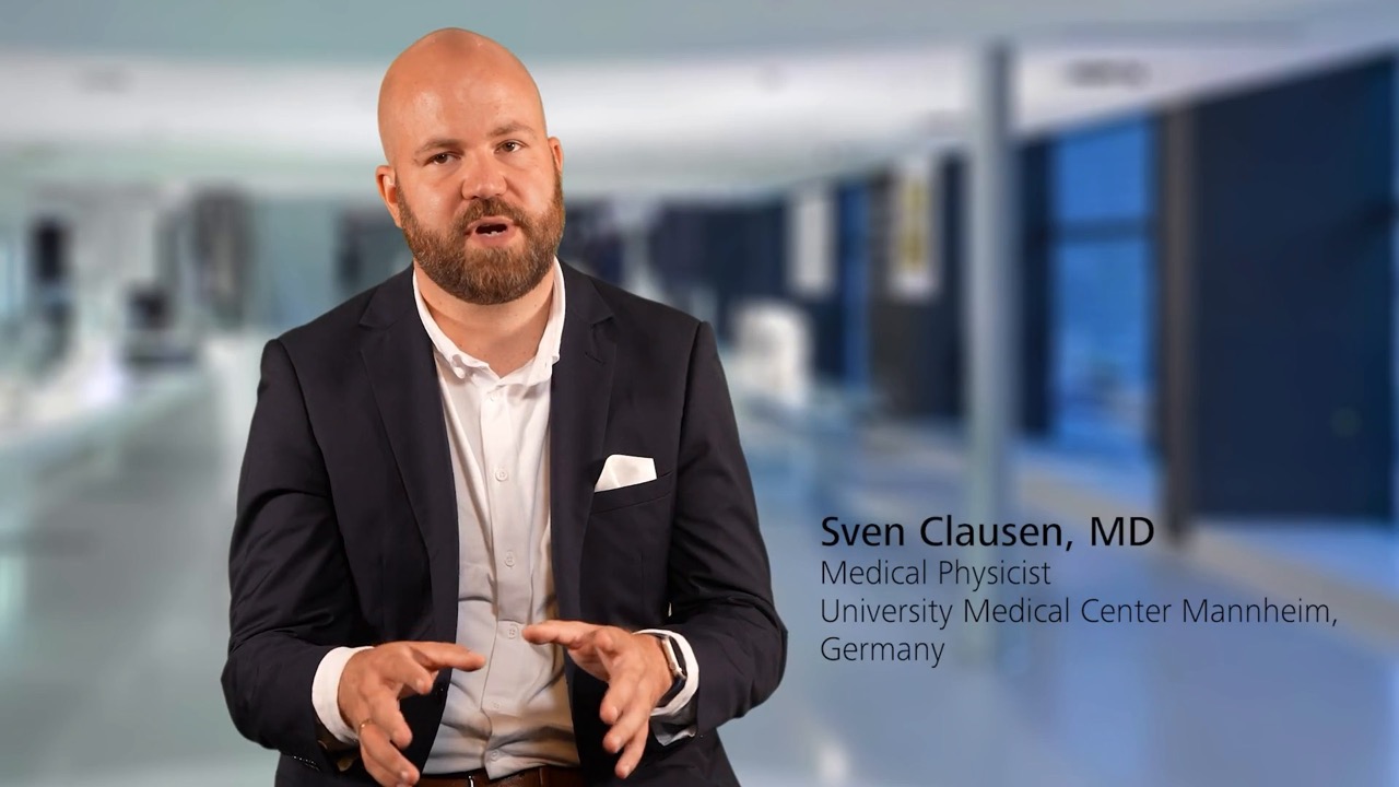 Sven Clausen, MD, Medical Physicist a the University Medical Center Mannheim, Germany, speaks in a professional setting with a blurred medical facility background and ZEISS branding context.