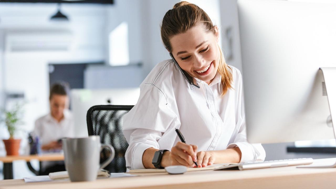 Jovem profissional animada sentada no seu local de trabalho