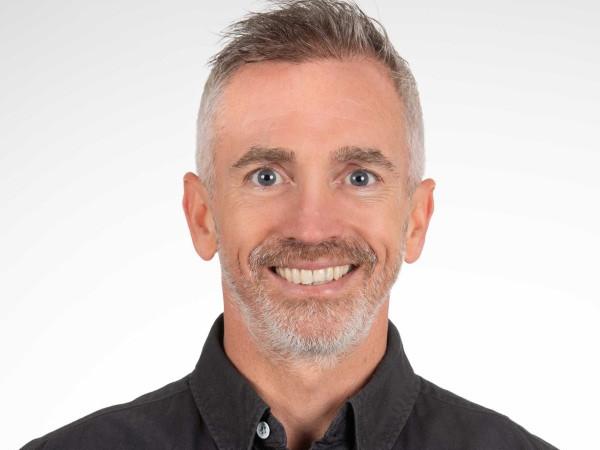 Dr. Richard Barry is wearing a black collared button-down shirt against a plain white background.