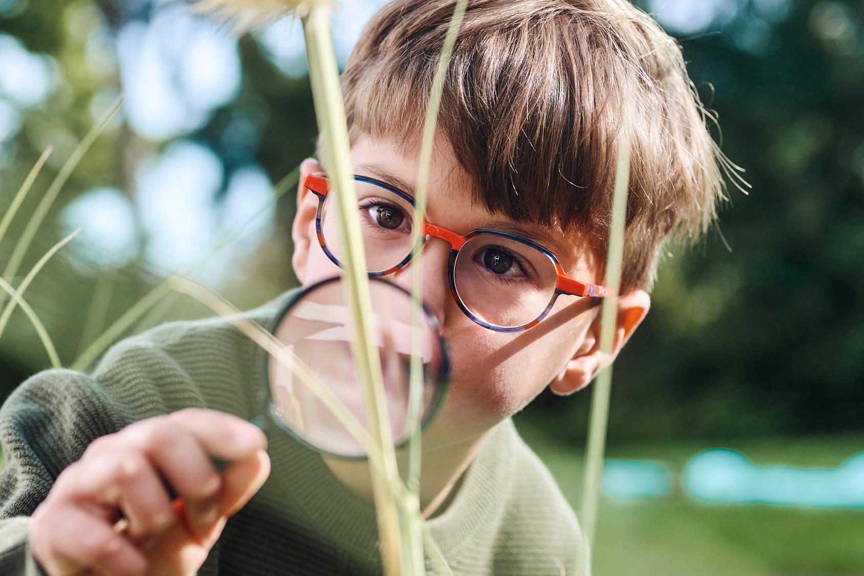 Bambino con una lente d'ingrandimento nella natura.
