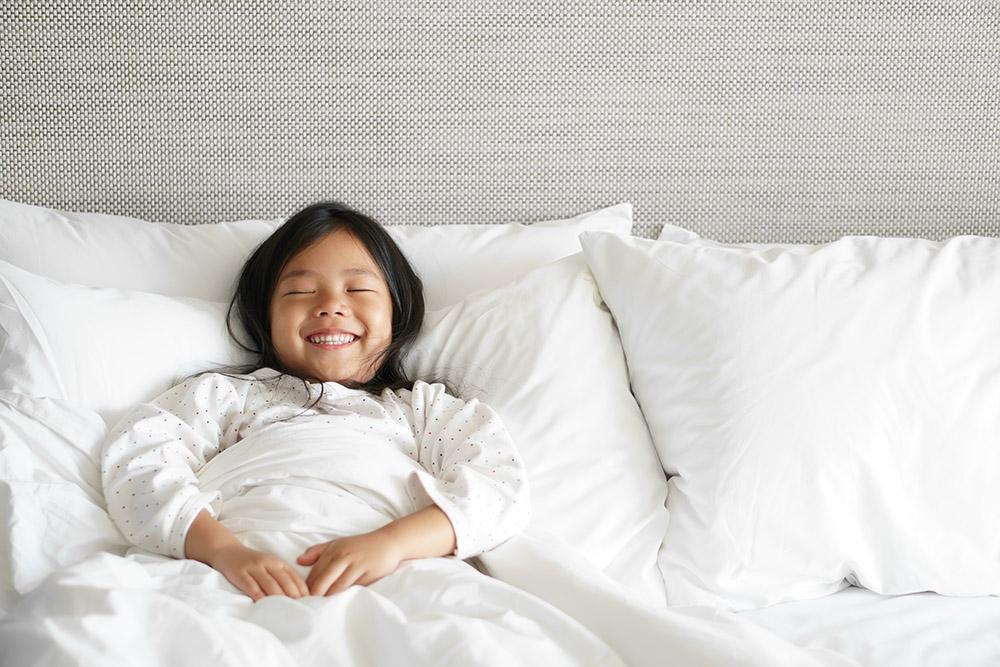 Happy child in white bedroom.