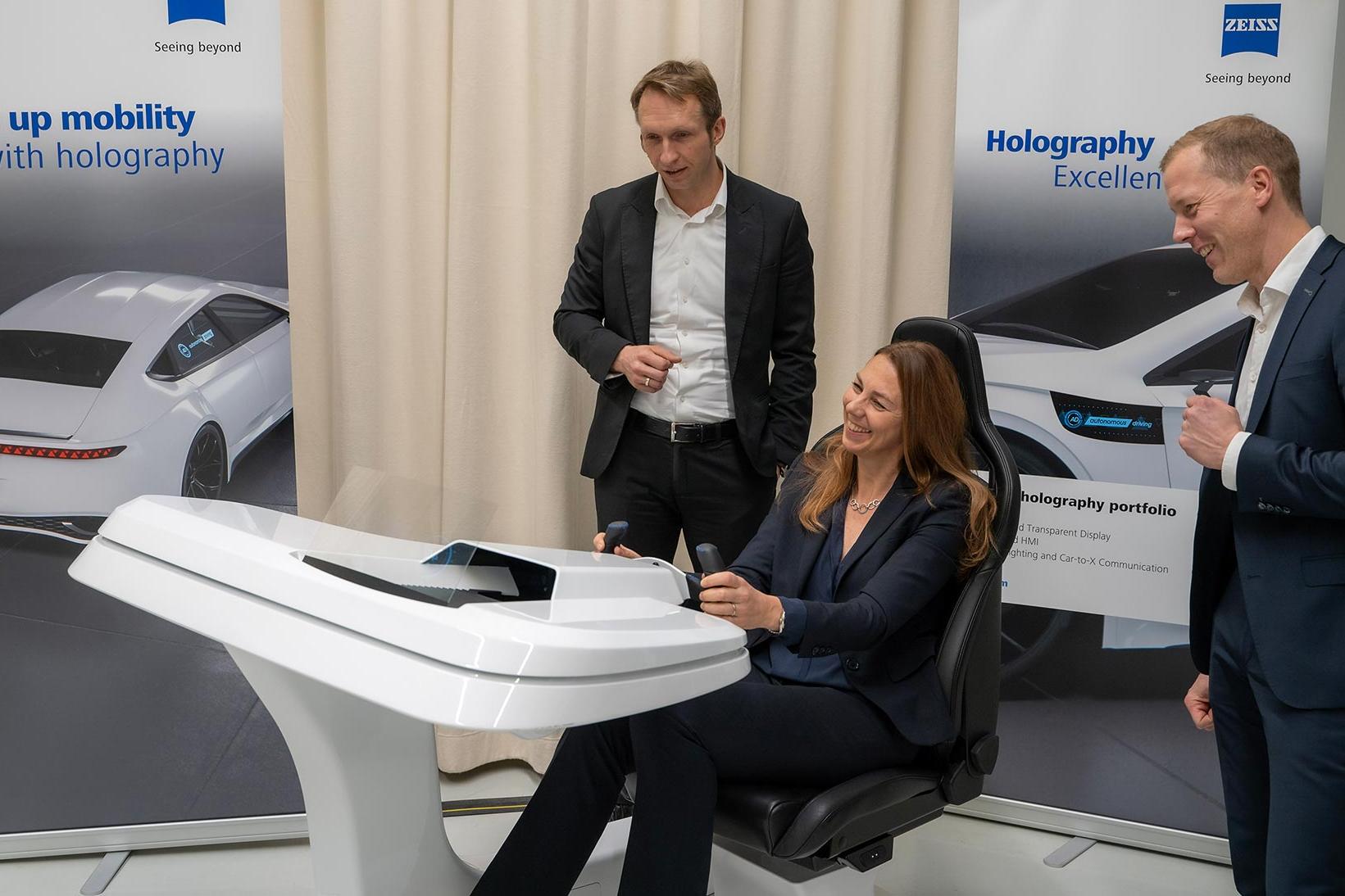 From left: André Kutz (Head of ZEISS Photonics and Optics), Dr. Ingrid Sebald (Board Member Technology, tesa), and Dr. Roman Kleindienst (Head of ZEISS Microoptics), examining the Holographic Transparent Display for automotive applications.