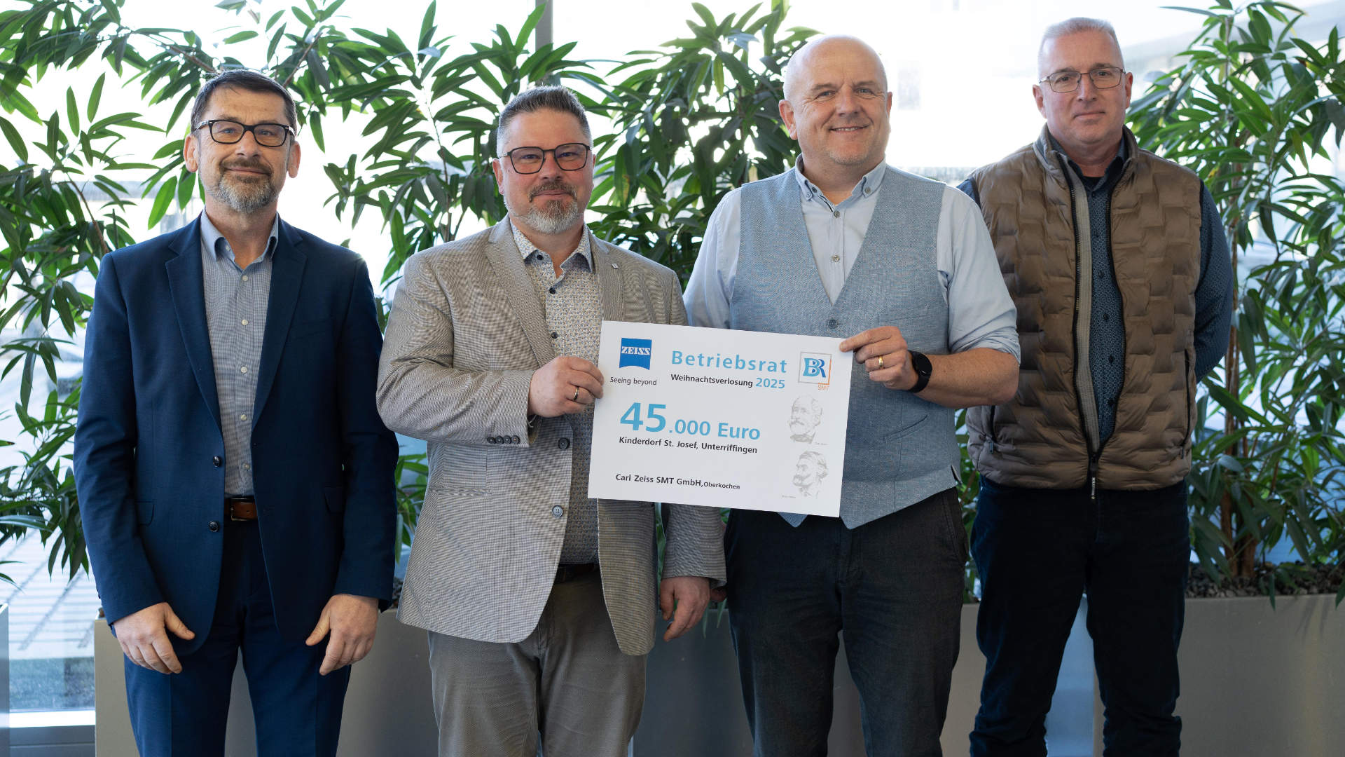 Four men, two of whom are holding a donation cheque.