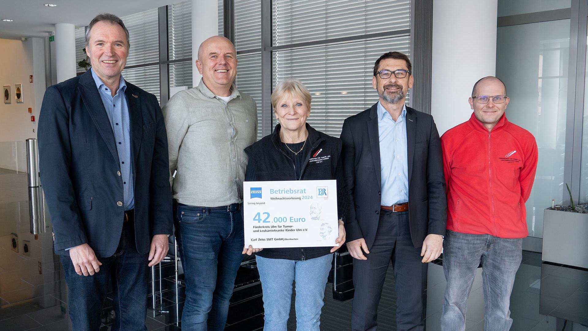 Four men and one woman hold a donation cheque.