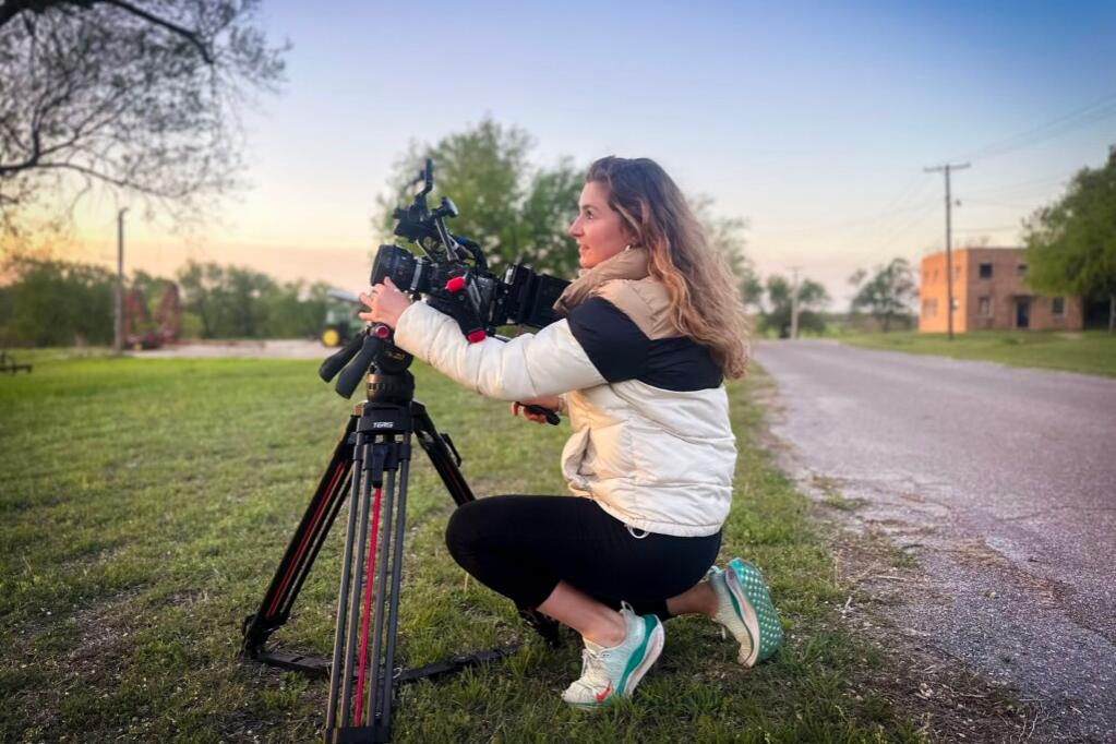 A camera operator films a scene using a professional camera setup equipped with ZEISS lenses in a studio environment.