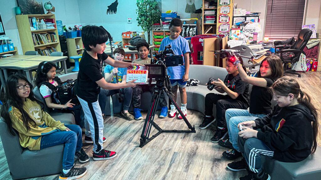 Two people are working with professional film production equipment, including a camera and monitor, in a studio setting featuring ZEISS lenses.