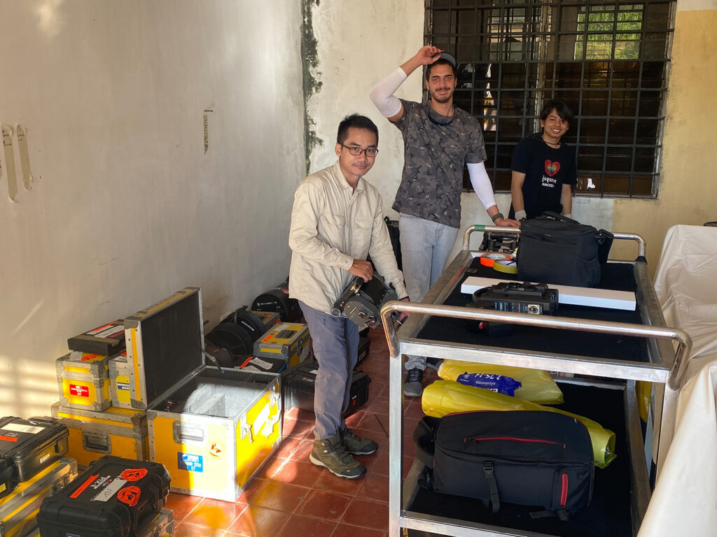 Two people are working with professional film production equipment, including a camera and monitor, in a studio setting featuring ZEISS lenses.