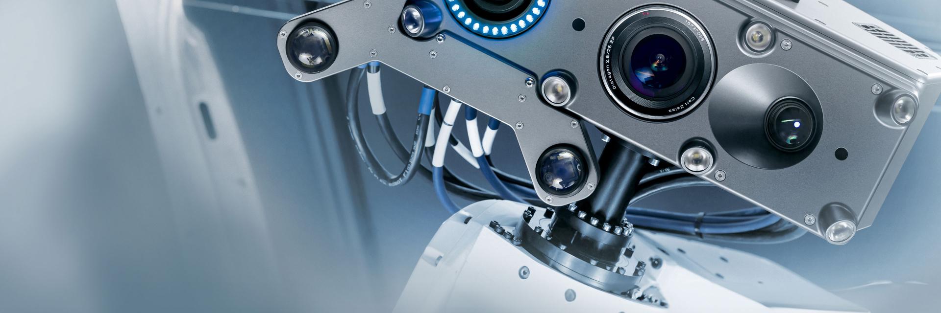 Close-up view of a high-precision industrial 3D scanning device with multiple lenses and sensors mounted on a robotic arm.