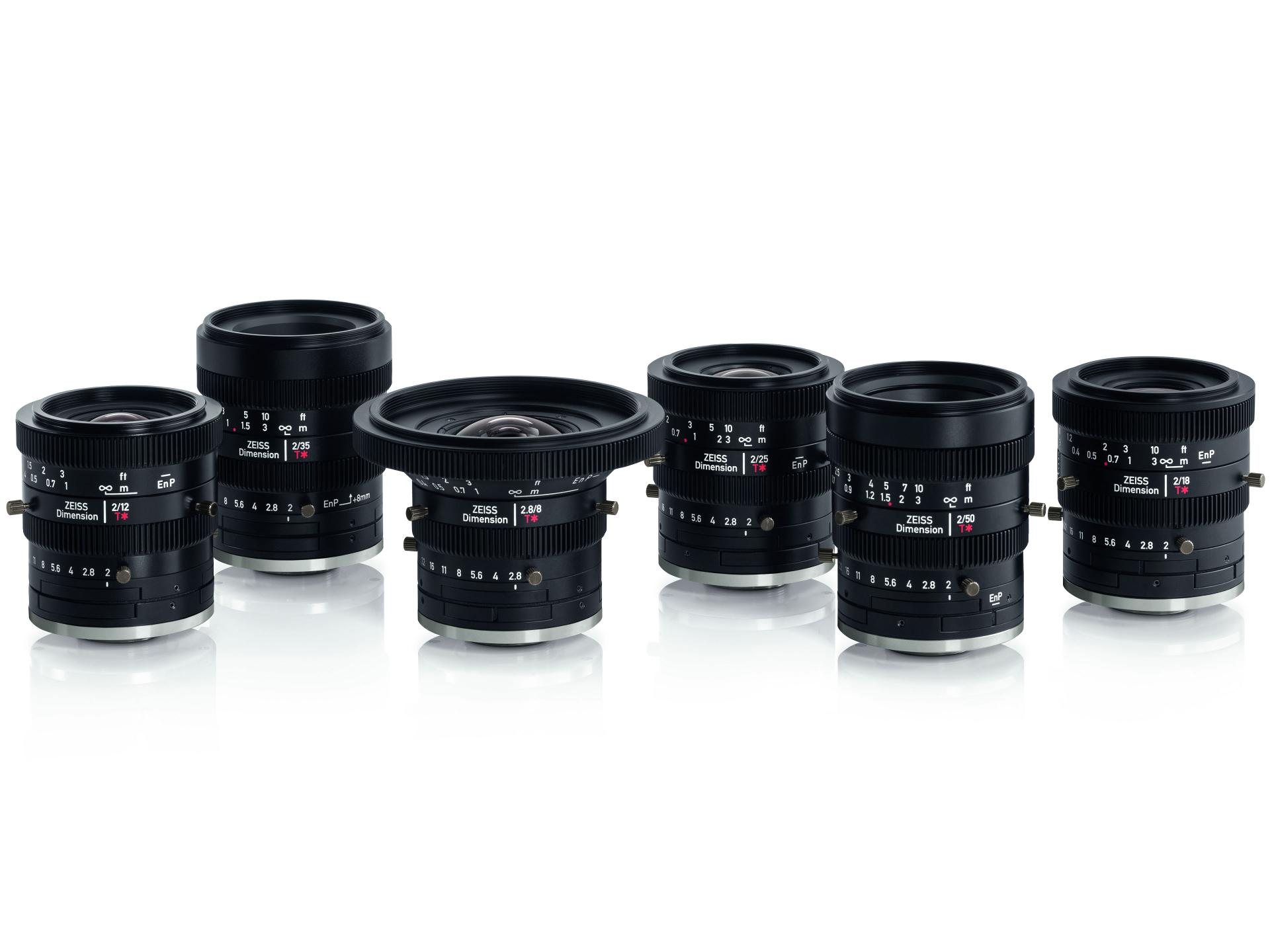Six professional ZEISS camera lenses are displayed in a row on a white reflective surface.