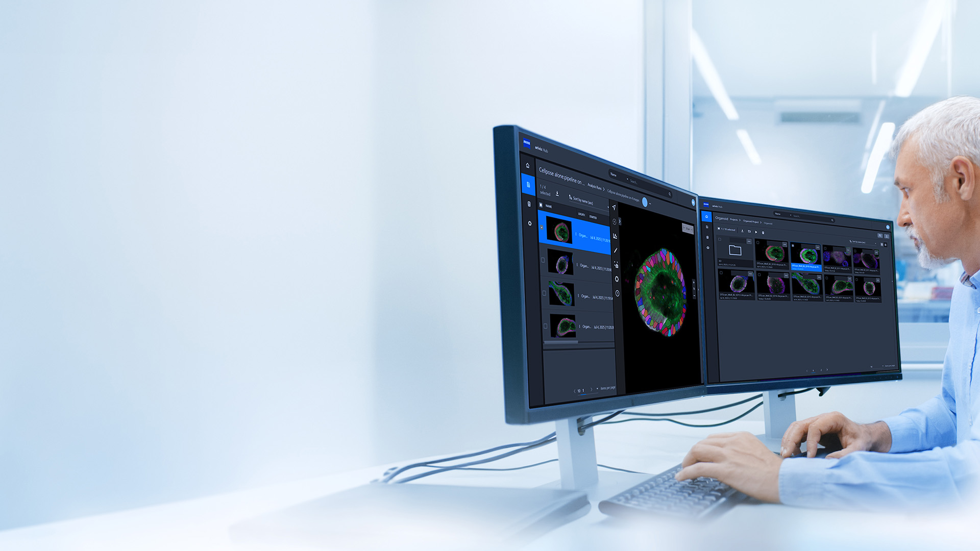 Man working on microscopy image analysis looking at two screens and using ZEISS arivis Hub DMS to analyse his image