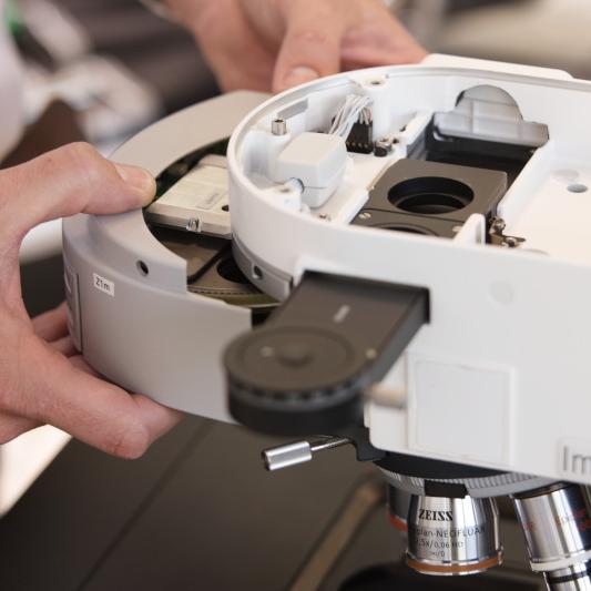 Close-up of the ZEISS Axio Imager.Z2m microscope with open housing, revealing internal components such as cables, electronics, and illumination modules. Laboratory setup showcasing advanced light microscopy instrumentation.