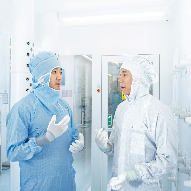 Two employees of SMT Process Control Solutions chat in the ZEISS SMT clean room
