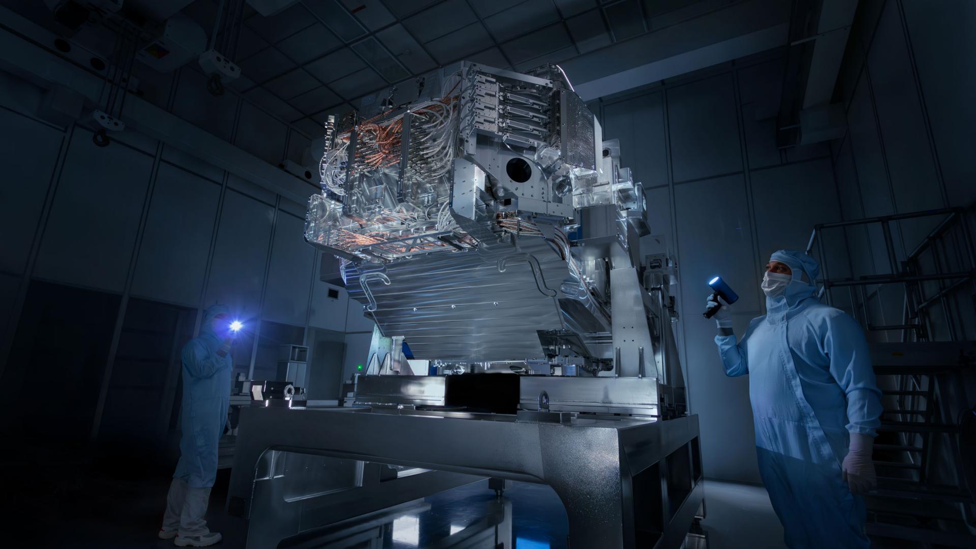 Two associates of ZEISS SMT working in the dark clean room wirth flashlights on the High-NA-EUV lithography