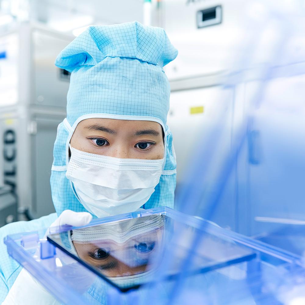 An employee working in the clean room with a photomask