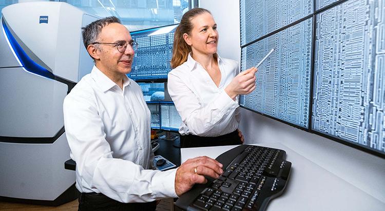 Two PCS-MultiSEM employees look at the latest technology on one screen
