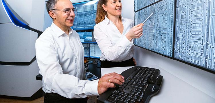 Two PCS-MultiSEM employees look at the latest technology on one screen