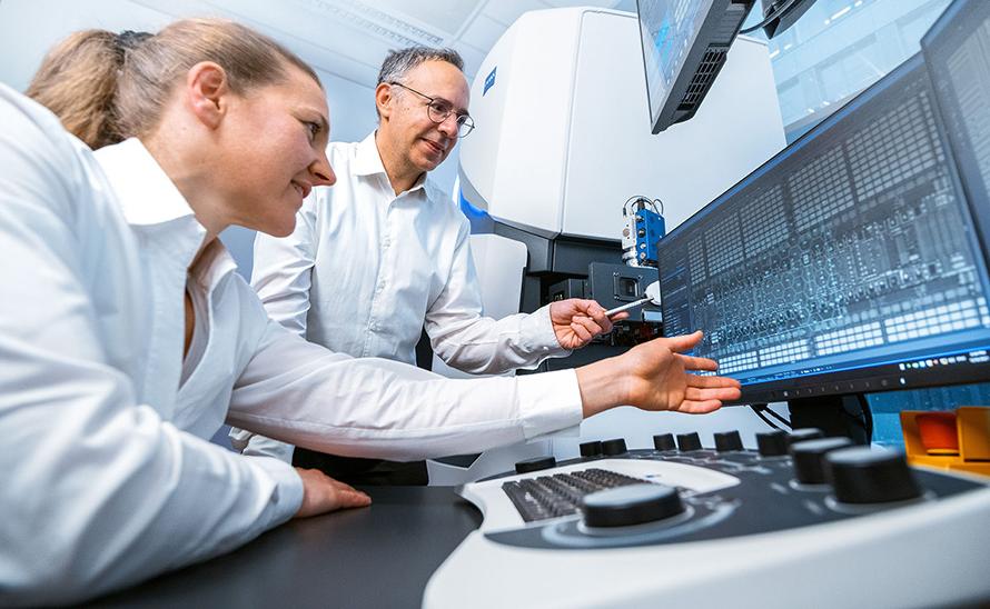 Two PCS-MultiSEM employees look at the latest technology on one screen