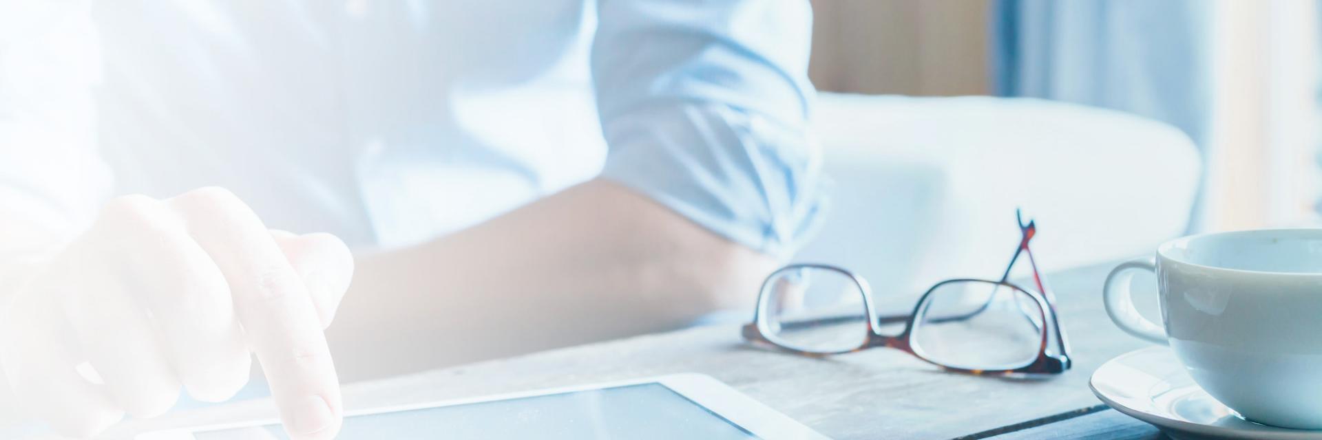 A man sits at the kitchen table reading ZEISS SMT publications on a tablet 