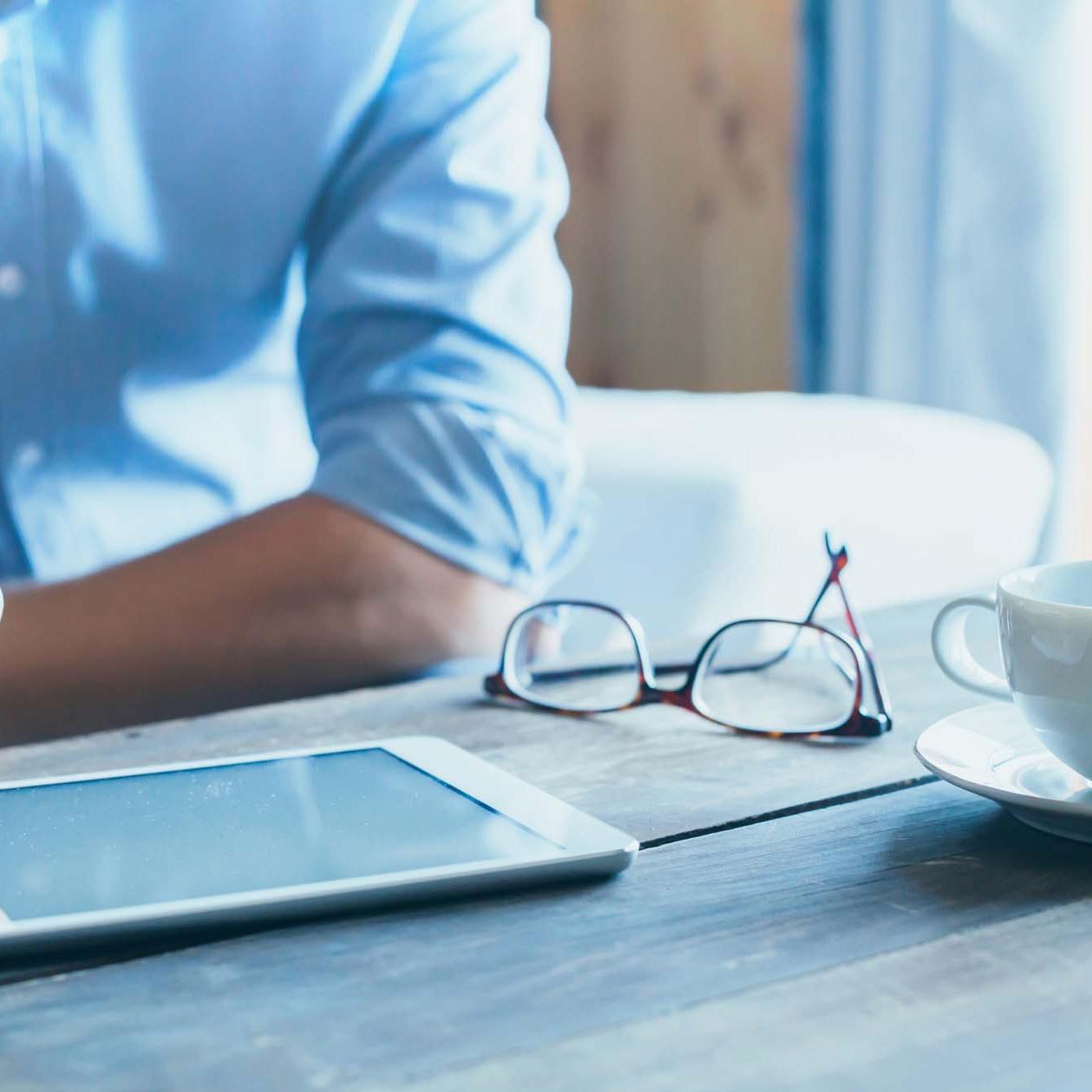 Man sitting at the kitchen table reading ZEISS SMT publications on his tablet