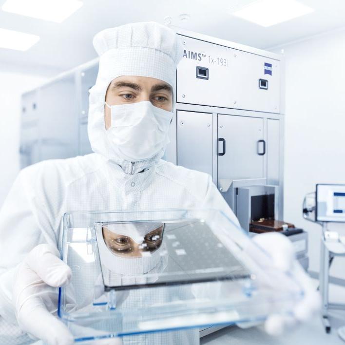 An emoloyee holding a photomask in his hands in the ZEISS SMT clean room 