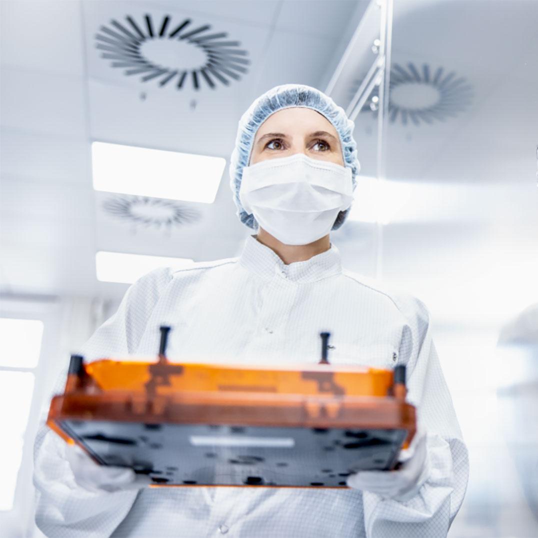 An employee in the SMT clean room with a photomask in her hand