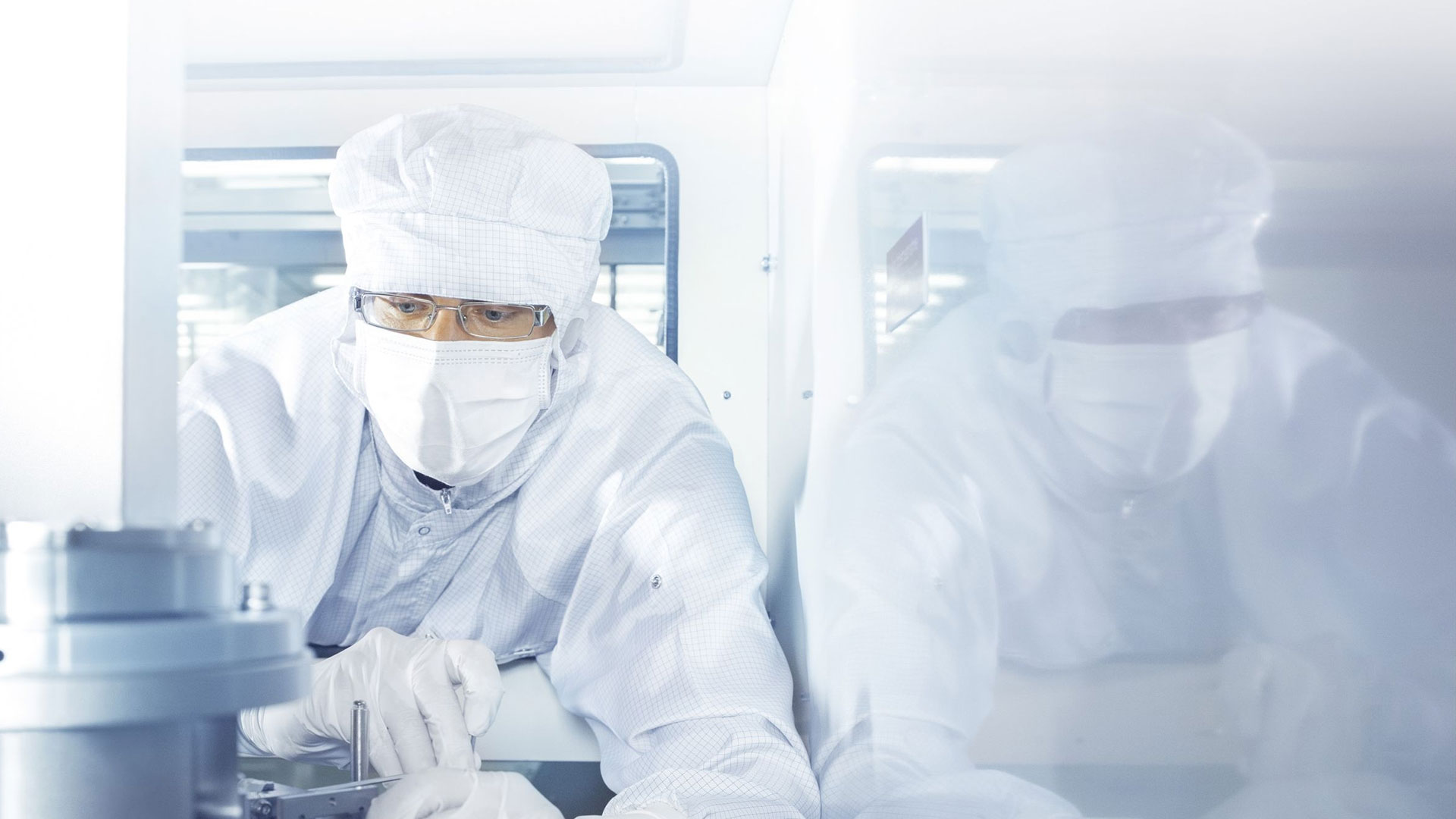 An employee works in the clean room on a tool from ZEISS SMT