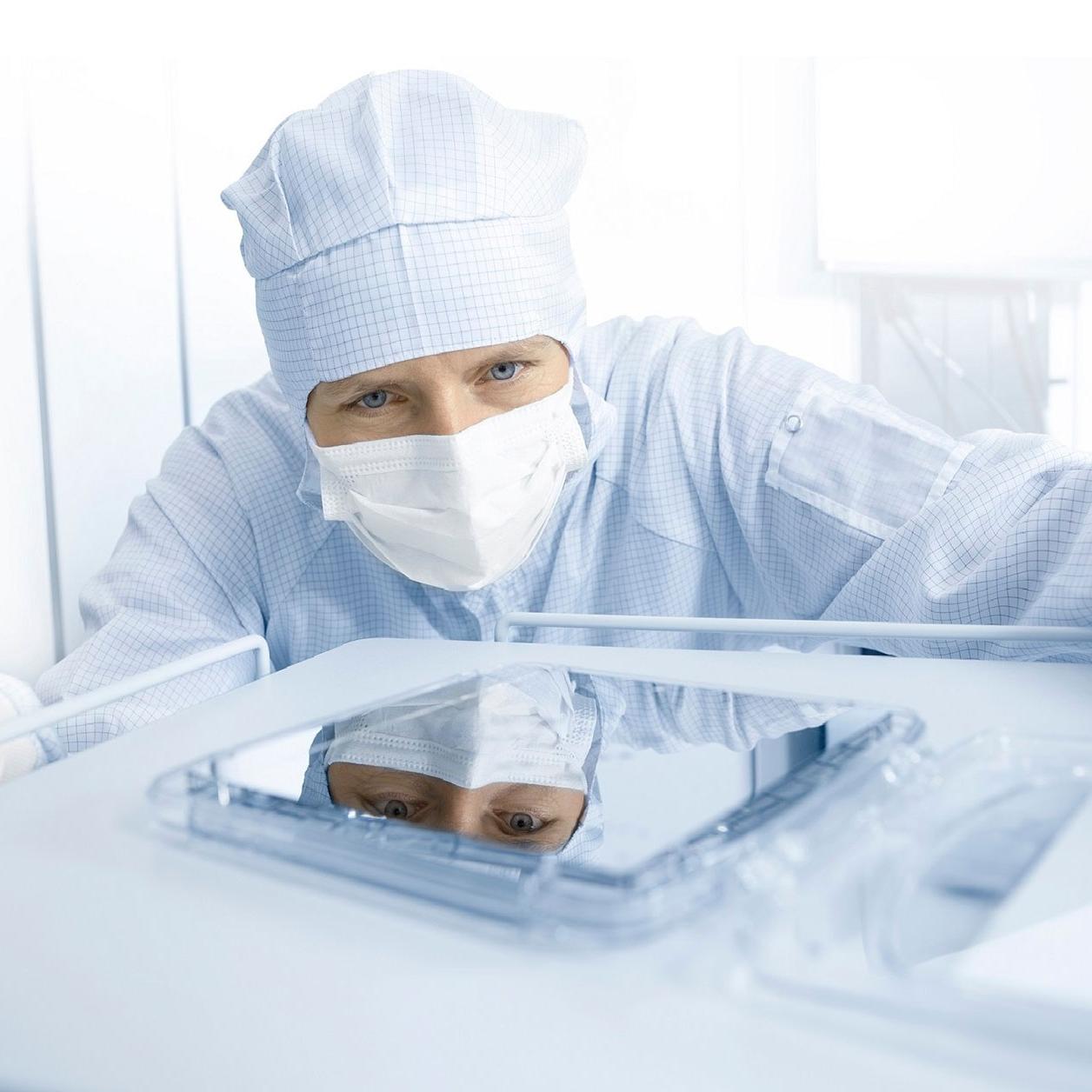 An employee looking in the ZEISS SMT clean room looking at a photomask 