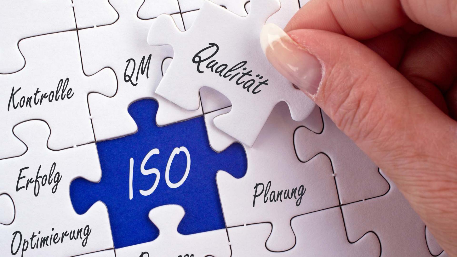 A woman completes a puzzle with inscriptions such as quality, planning, processes or ISO