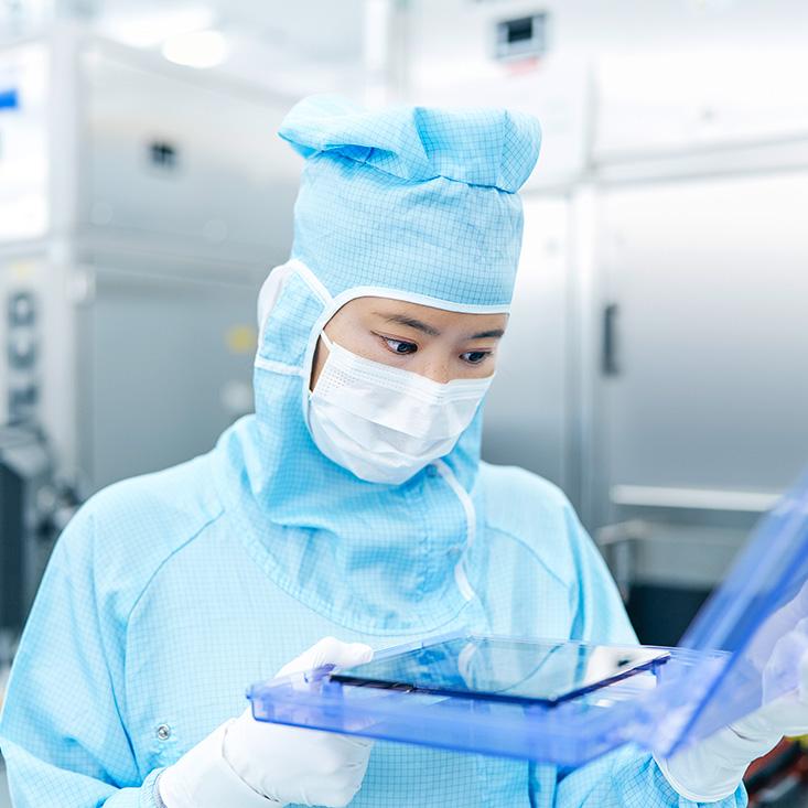 An employee carefully checks the photomasks in the clean room 