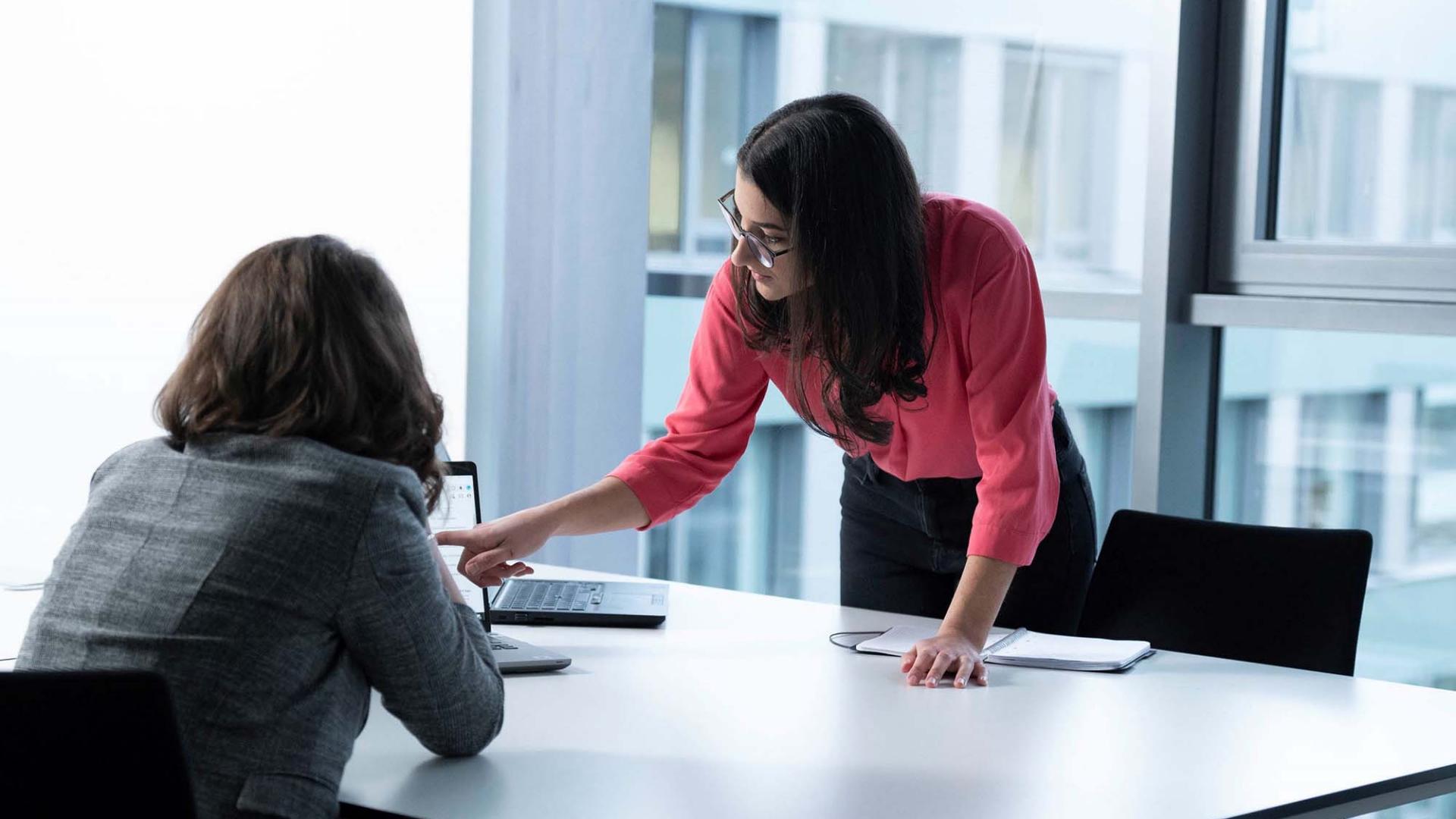 A female manager explains something on a laptop to a female colleague at ZEISS SMT.