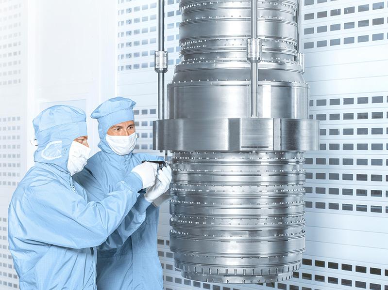 Two employees work on a DUV lens from the Starlith® 19xyi series in the clean room at ZEISS Semiconductor Manufacturing Technology.