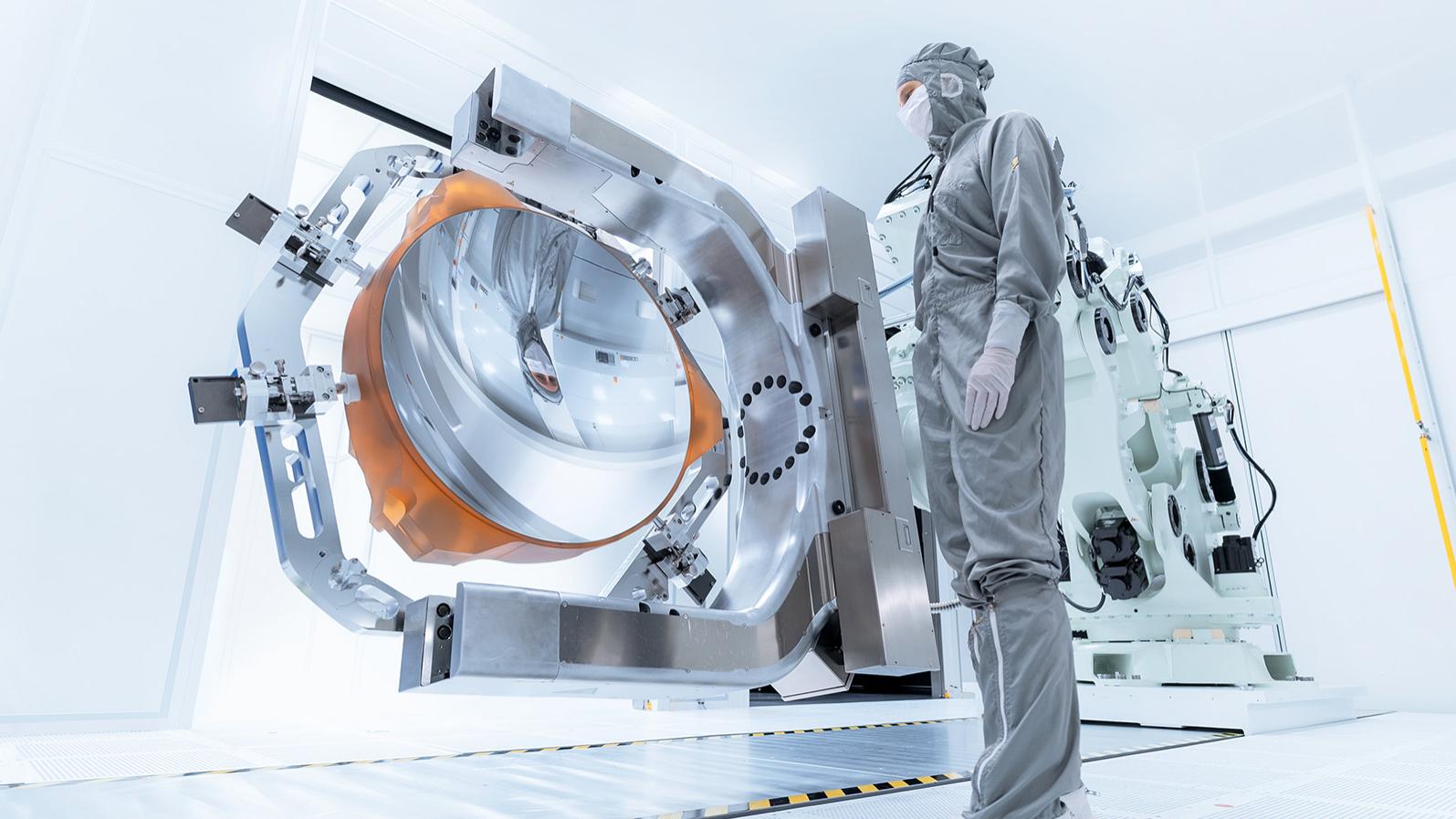 An employee looks at the coated mirror of High-NA-EUV technology in the clean room of ZEISS Semiconductor Manufacturing Technology
