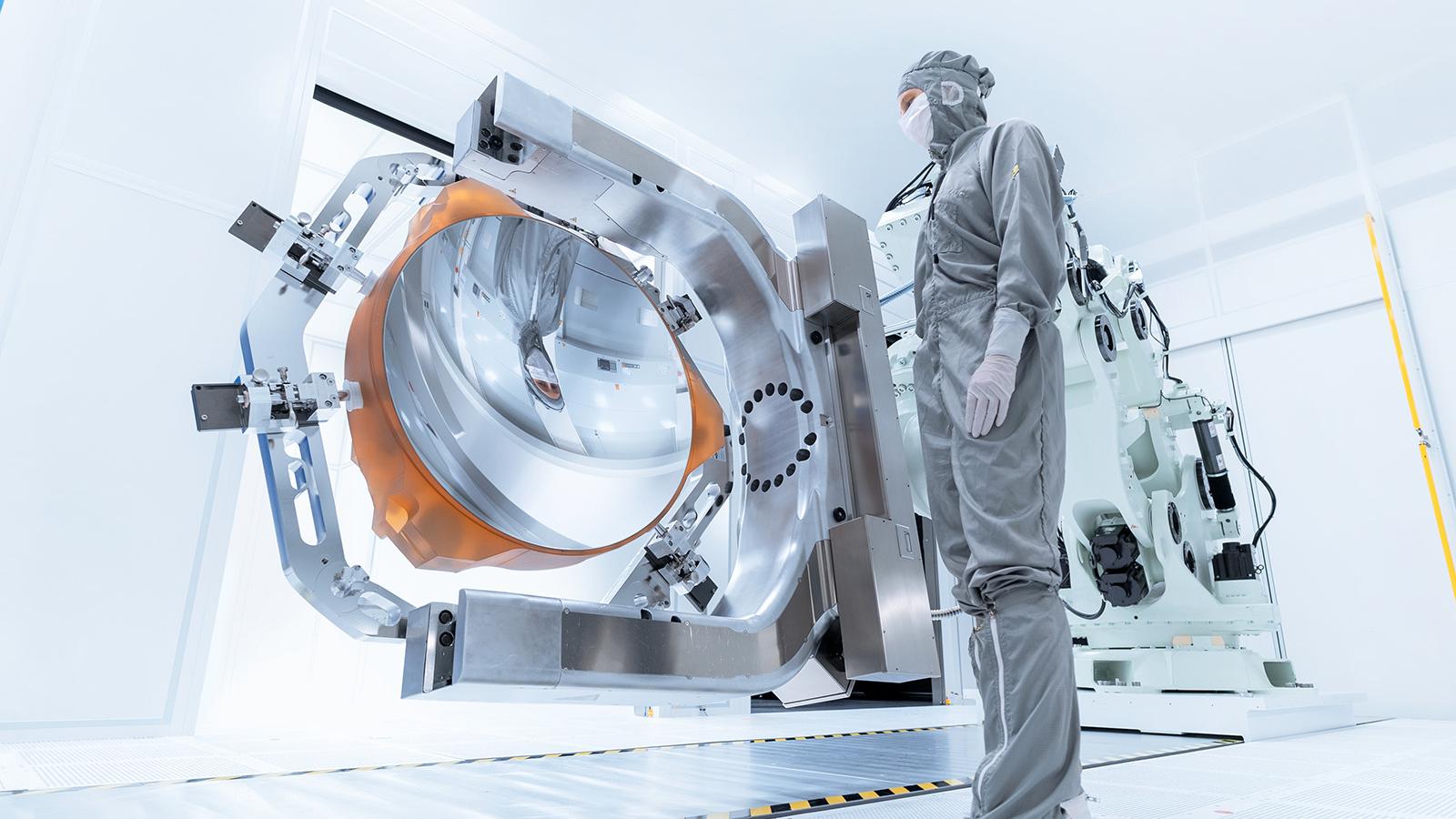 An employee looks at the coated mirror of High-NA-EUV lithography in the clean room of ZEISS Semiconductor Manufacturing Technology