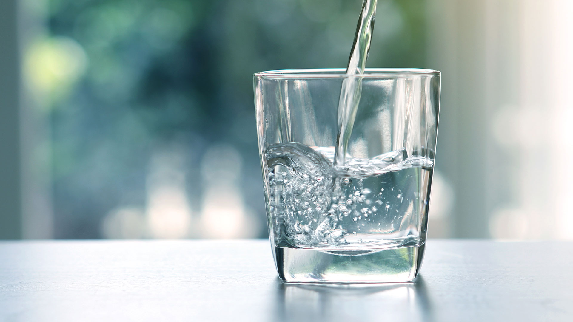 Close up the pouring purified fresh drink water from the bottle on table in living room