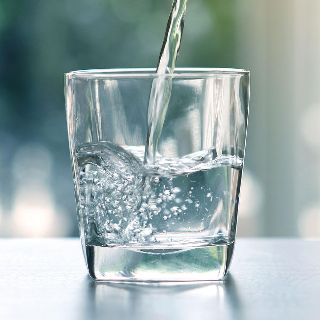 Close up the pouring purified fresh drink water from the bottle on table in living room