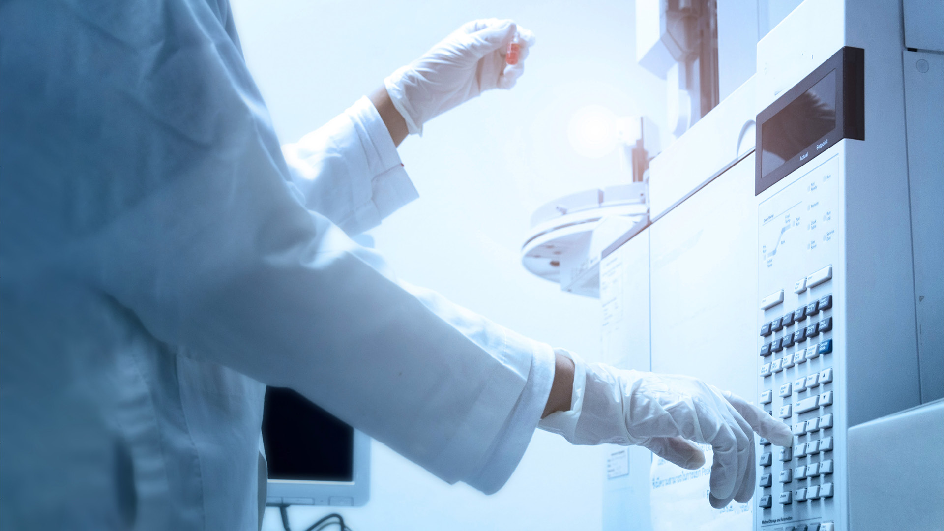 scientist holds an amber vial and press the control button of GC chromatography