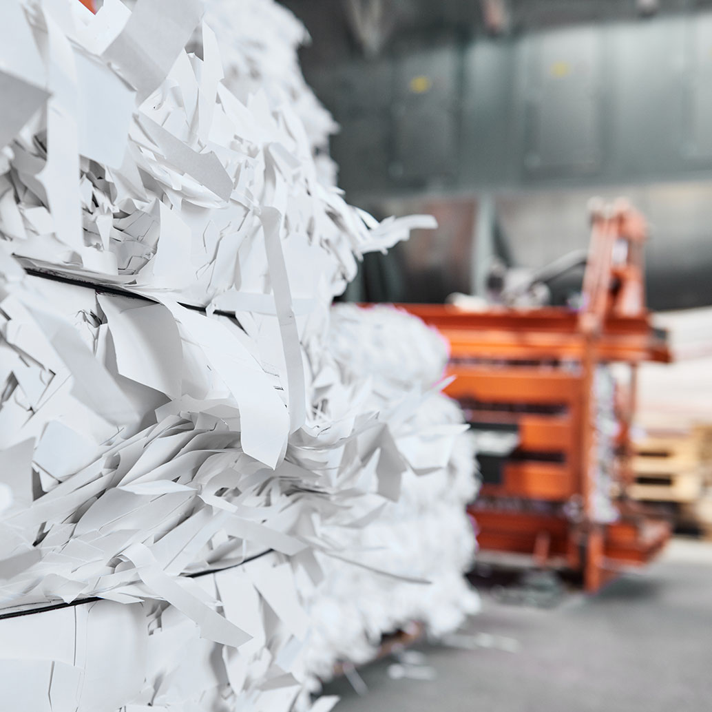 A paper recycling factory plant shredding machine, shredding waste paper into square bails, ready to be pulped and reused. Recycle waste materials to offset pollution and save the planet.