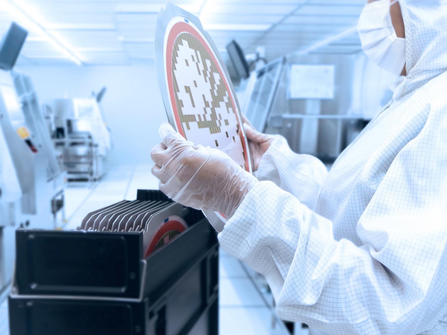 Employee in the clean room holds wafers in his hands