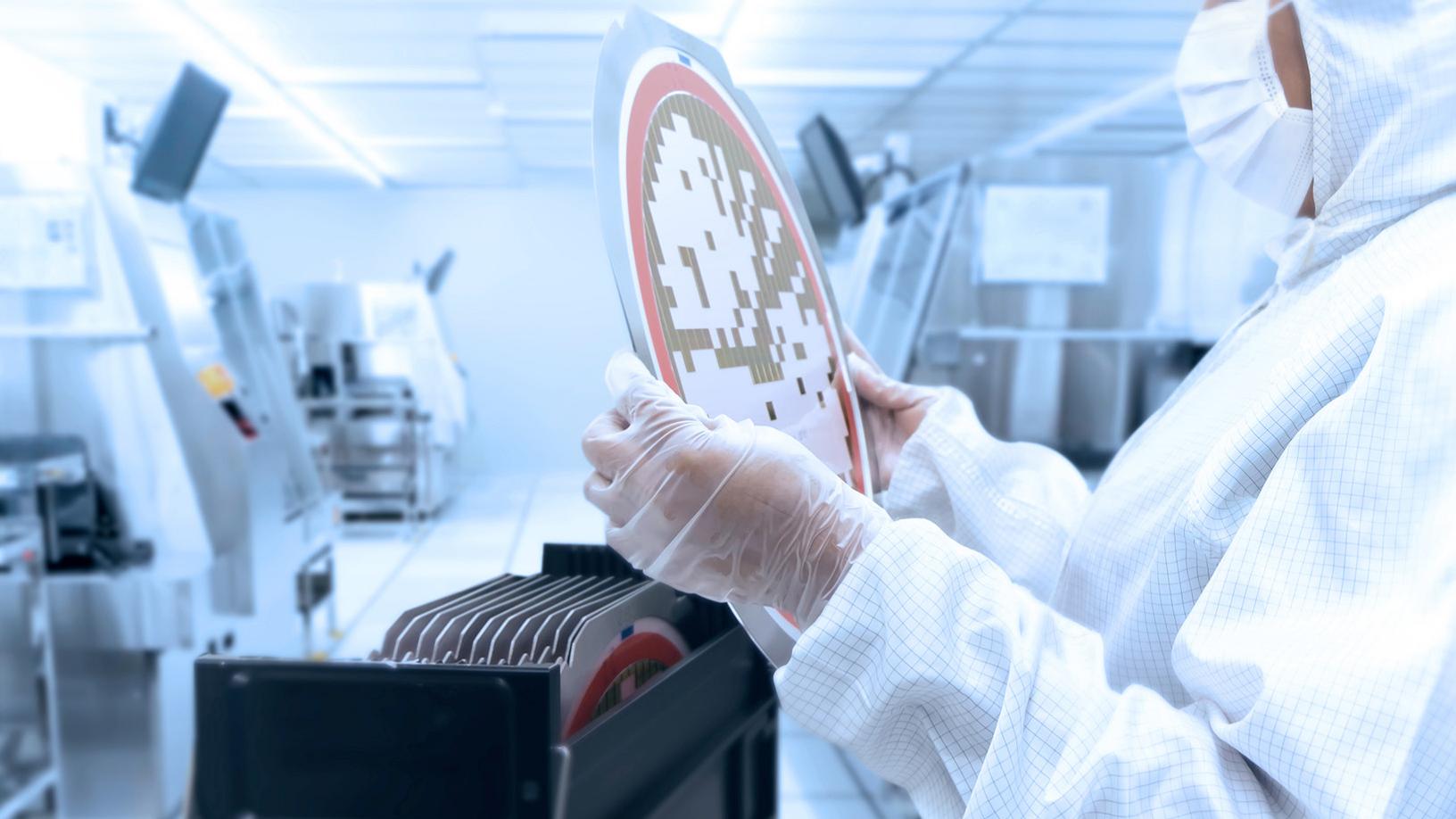 Employee in the clean room holds wafers in his hands