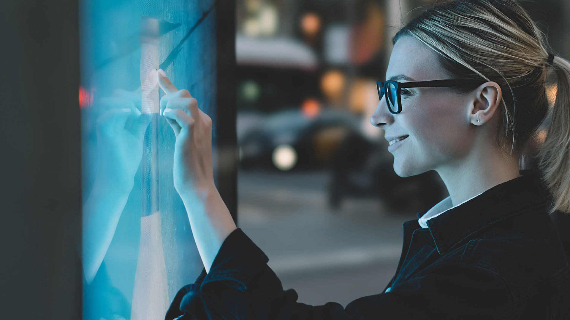 Smiling female standing at big display with advanced digital technology, display glass