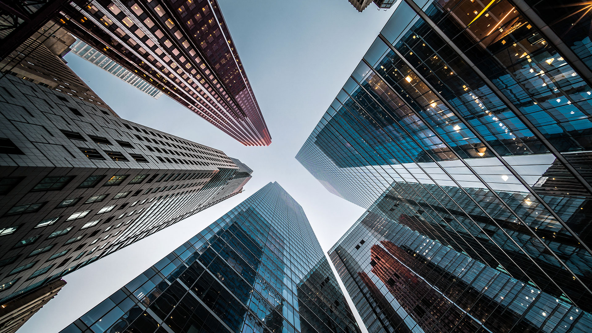 Looking up at high rise office building architecture against blue sky in the financial district of a modern metropolis, architectural glass