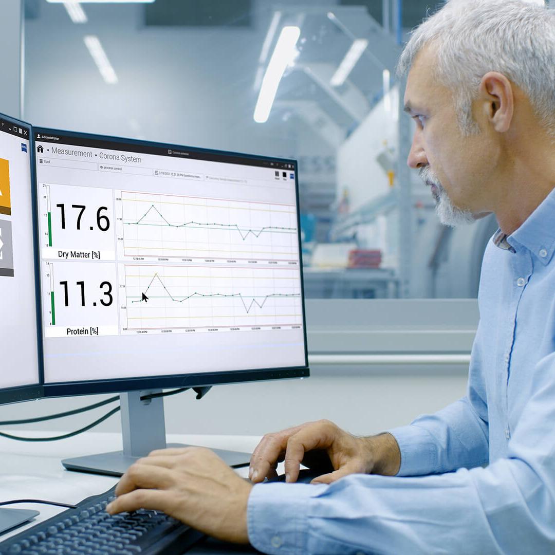 engineer sits in front of the computer in a production environment in his office, the screens show the interface of the inprocess software 