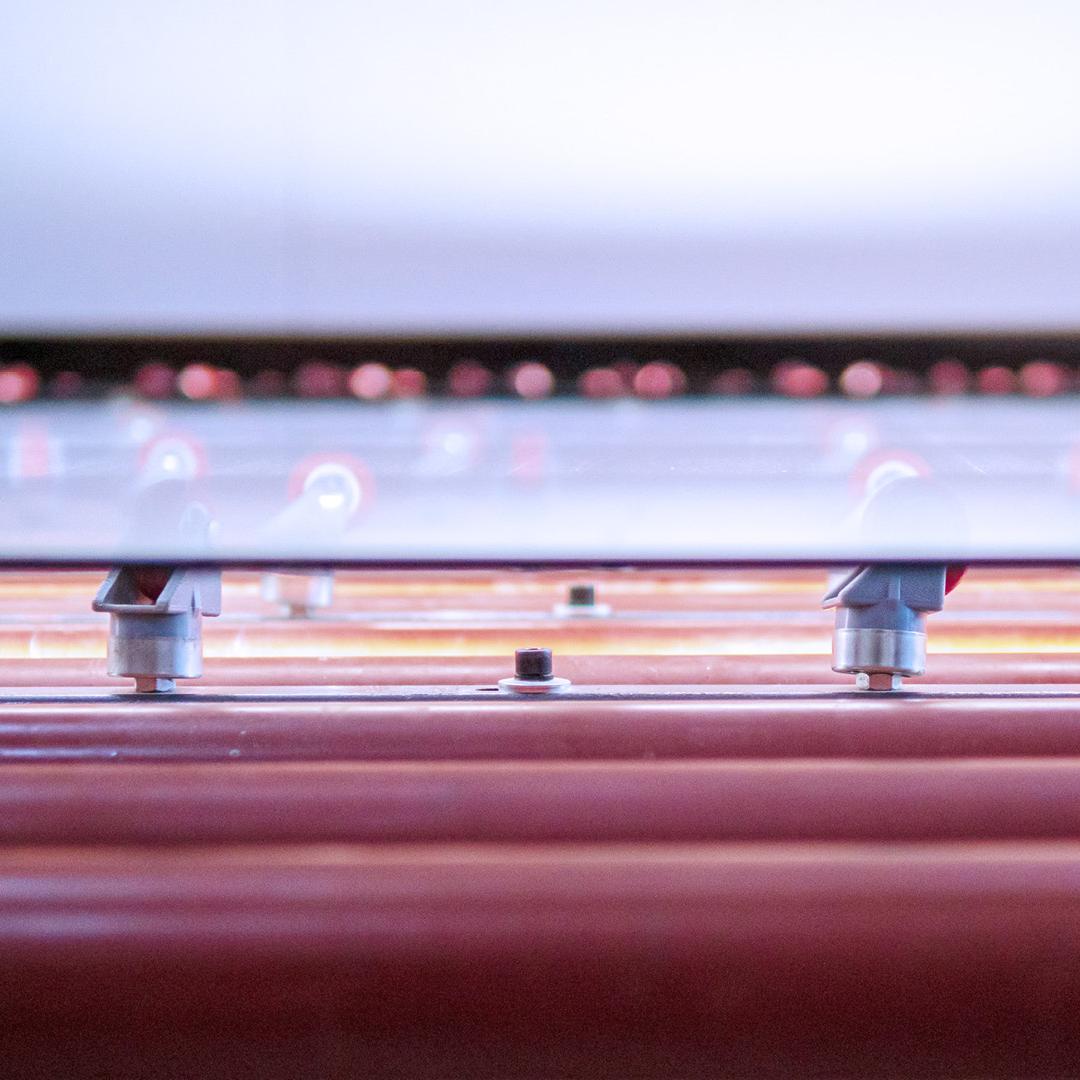 close up of glass sheet on rollers in glass factory