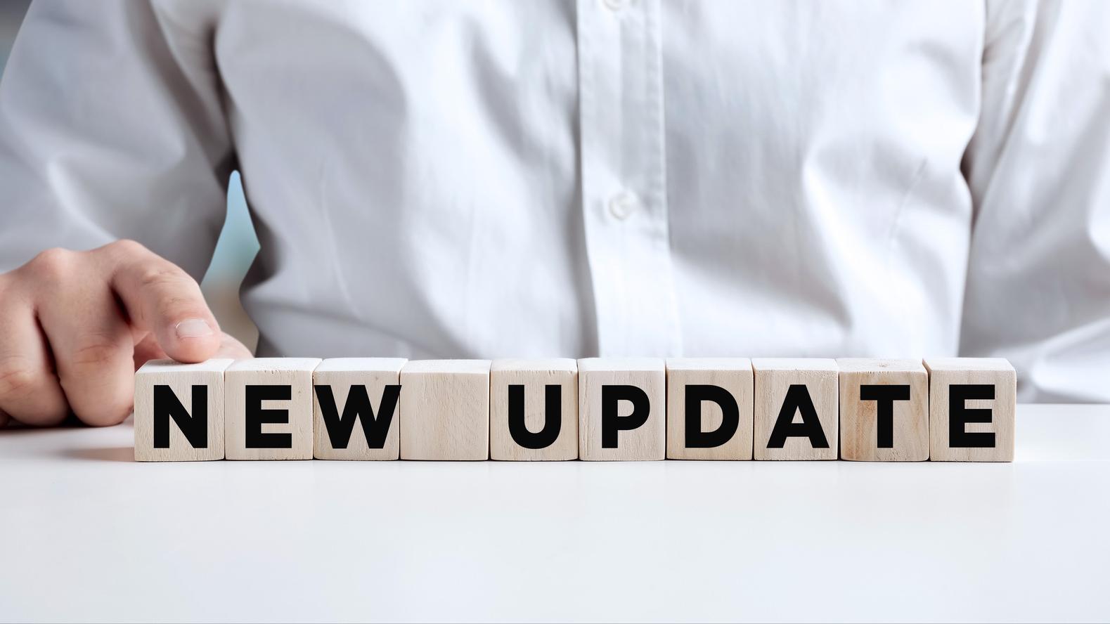 A businessman presses his finger on a wooden cube with the word &quot;New Update&quot; on it