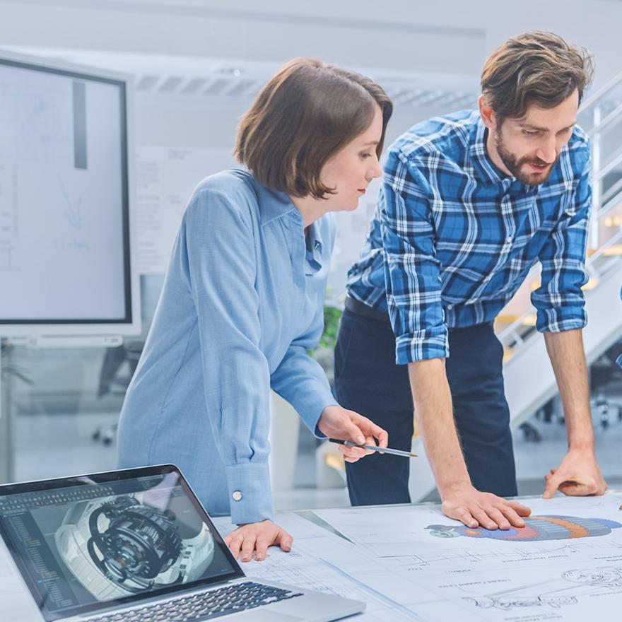  Engineers and technicians in a meeting gather around table with engine design technical drafts, have discussion, analyze technology