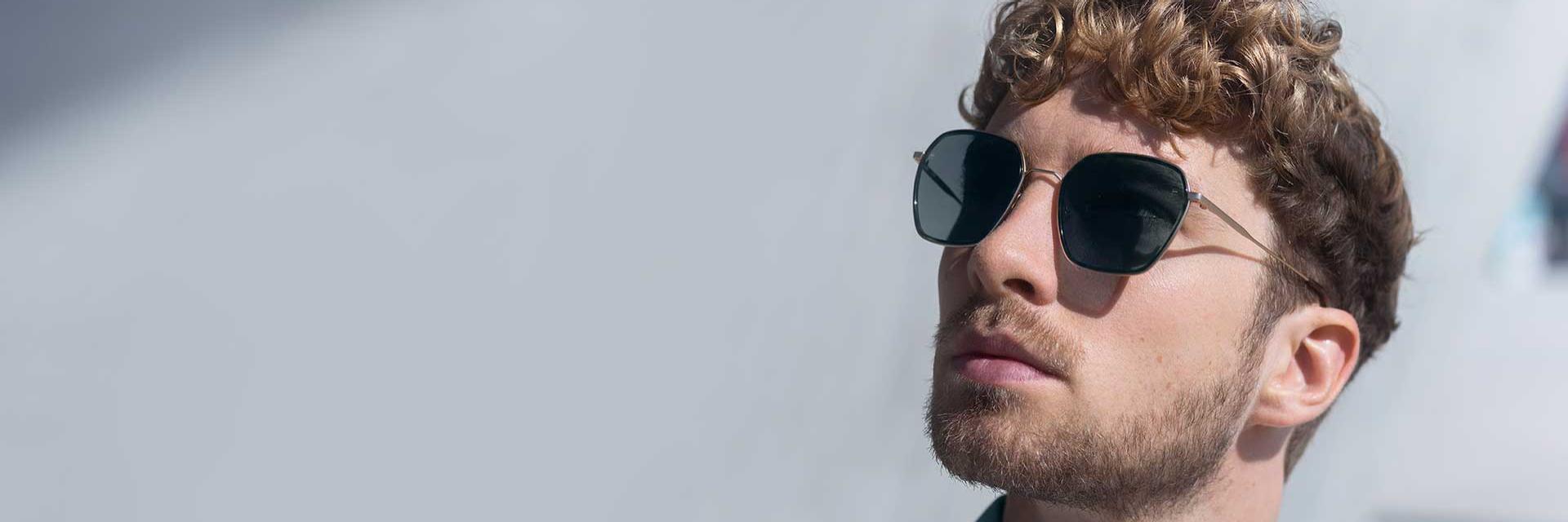 A man wears glasses with coloured lenses and looks upwards.